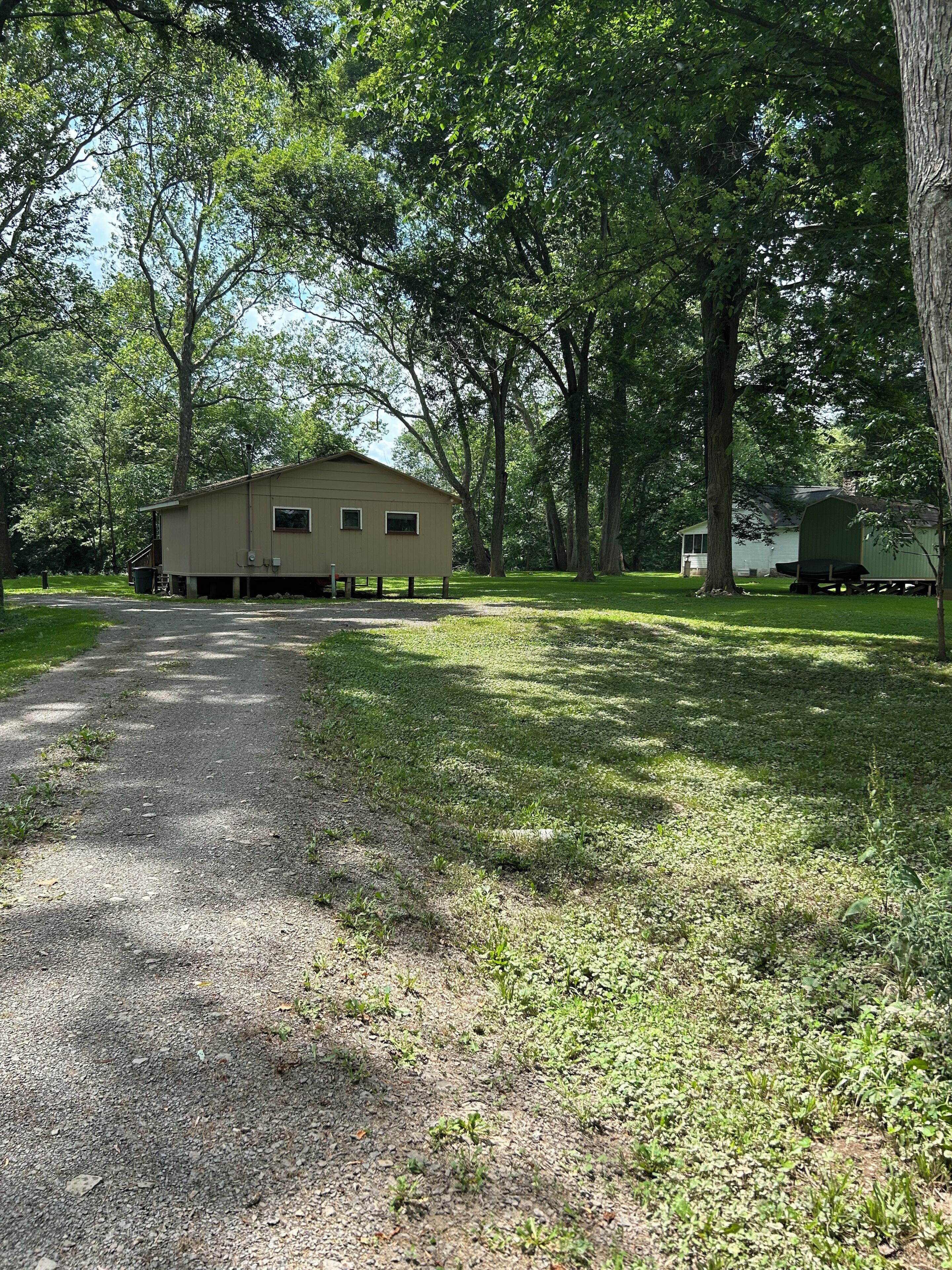 A building with a simple, single-story structure, surrounded by trees and a gravel path.