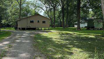 A building with a simple, single-story structure, surrounded by trees and a gravel path.