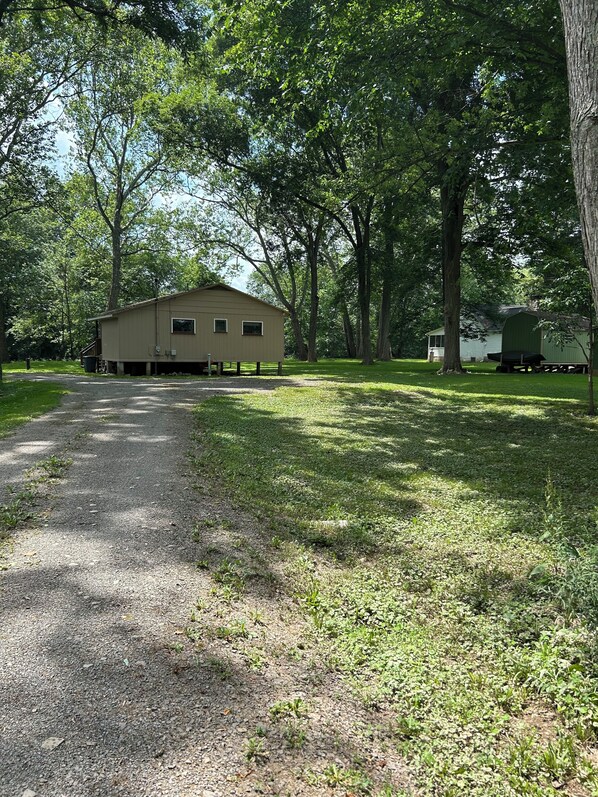 A building with a simple, single-story structure, surrounded by trees and a gravel path.