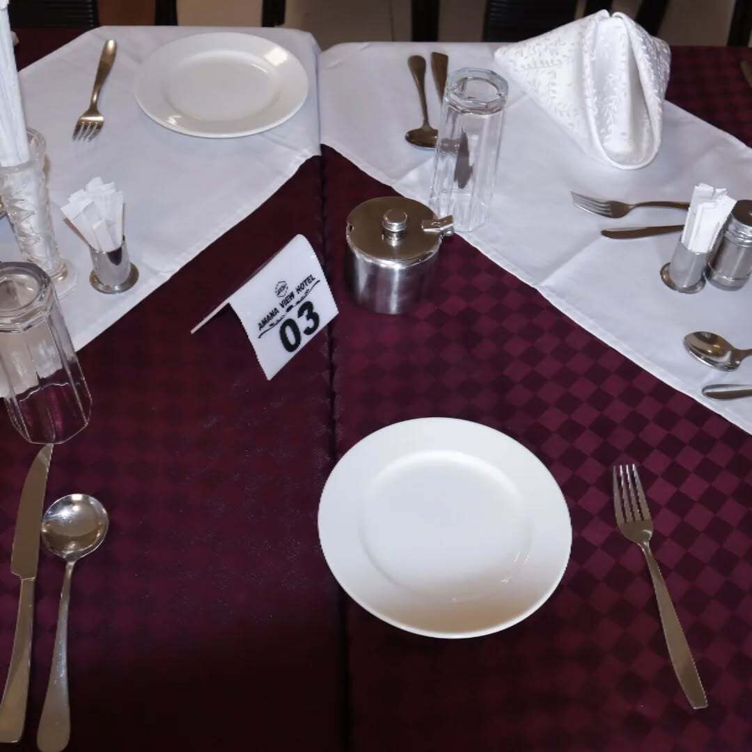 Una mesa para dos con un número identificador, un vaso de agua y salero y pimentero.