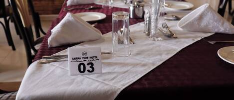 A neatly set dining table with a white tablecloth, numbered placemats, and silverware.