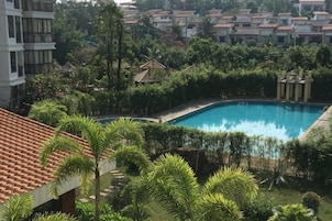 Una piscina rodeada de abundante vegetación y un edificio con techo de tejas.