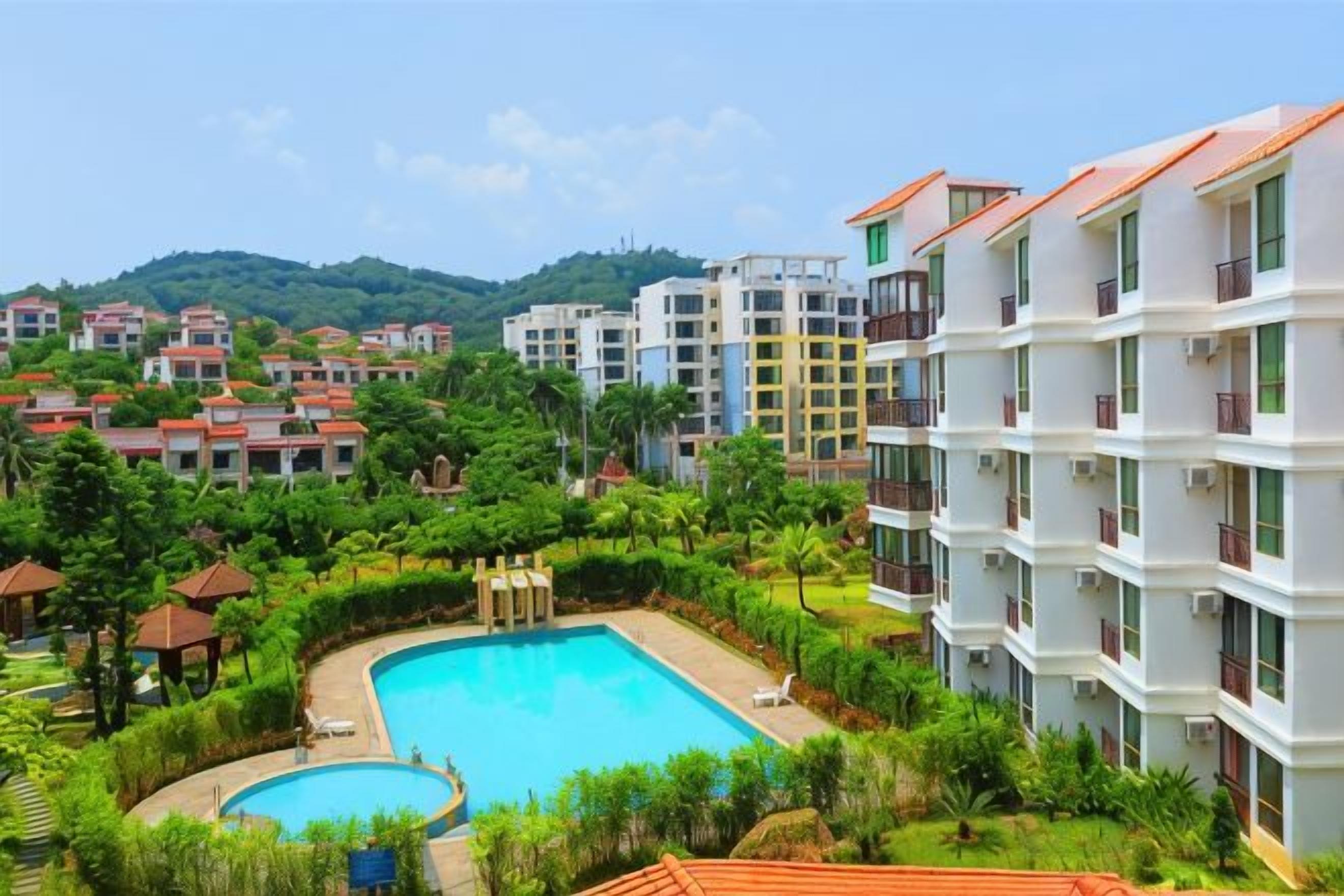 A resort with multiple buildings, a swimming pool, and lush greenery.