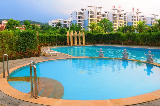 A swimming pool with a circular design, surrounded by a tiled deck and metal railings.