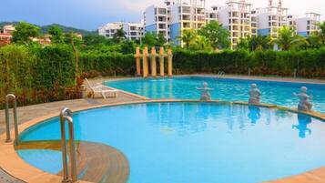 A swimming pool with a circular design, surrounded by a tiled deck and metal railings.