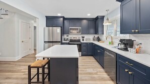 A modern kitchen with dark cabinets, stainless steel appliances, and a white countertop.