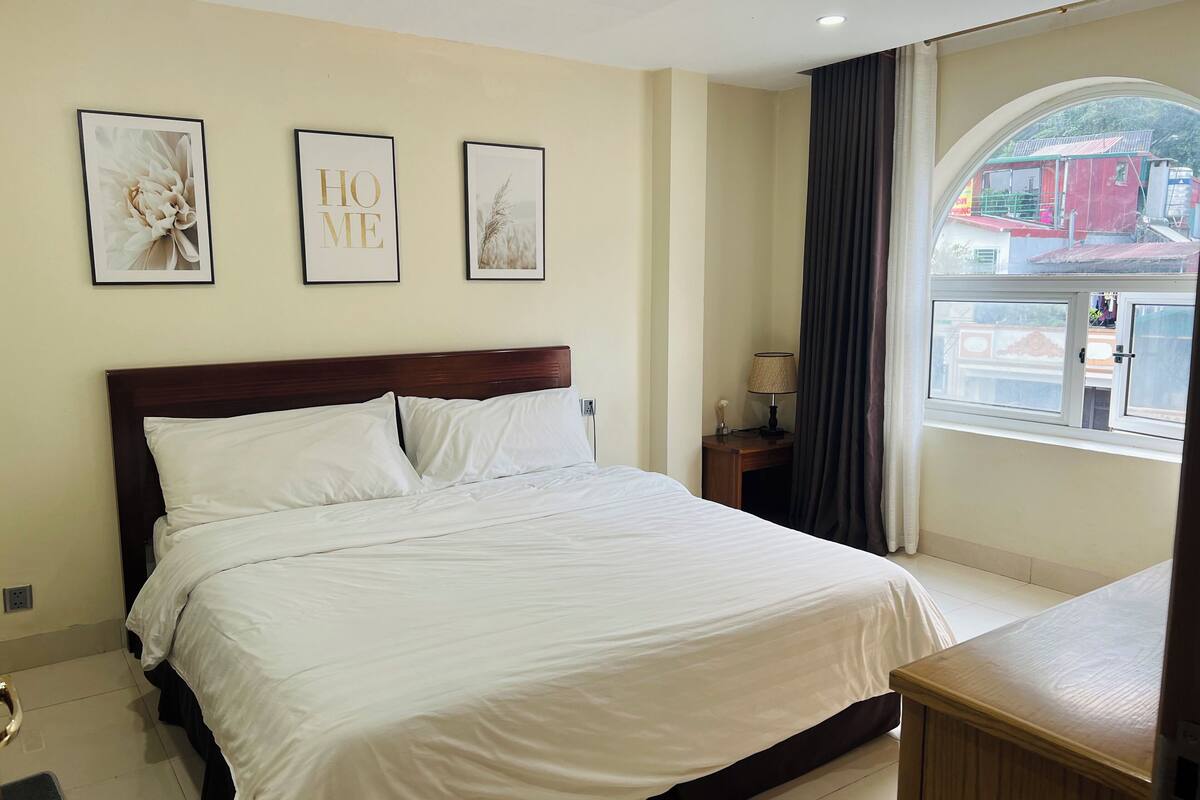 A hotel room with a large bed, a nightstand with a lamp, and three framed pictures on the wall.