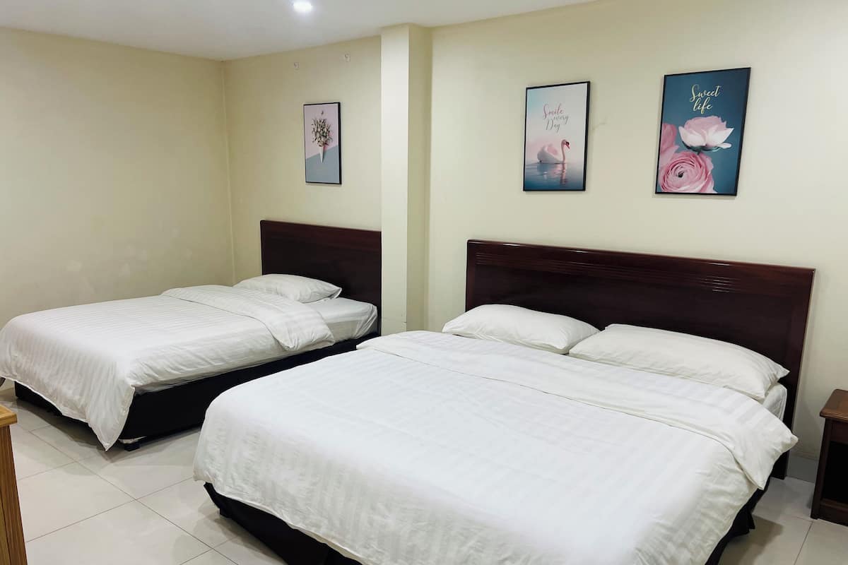 A hotel room with two single beds, a wooden headboard, and two wall-mounted pictures.