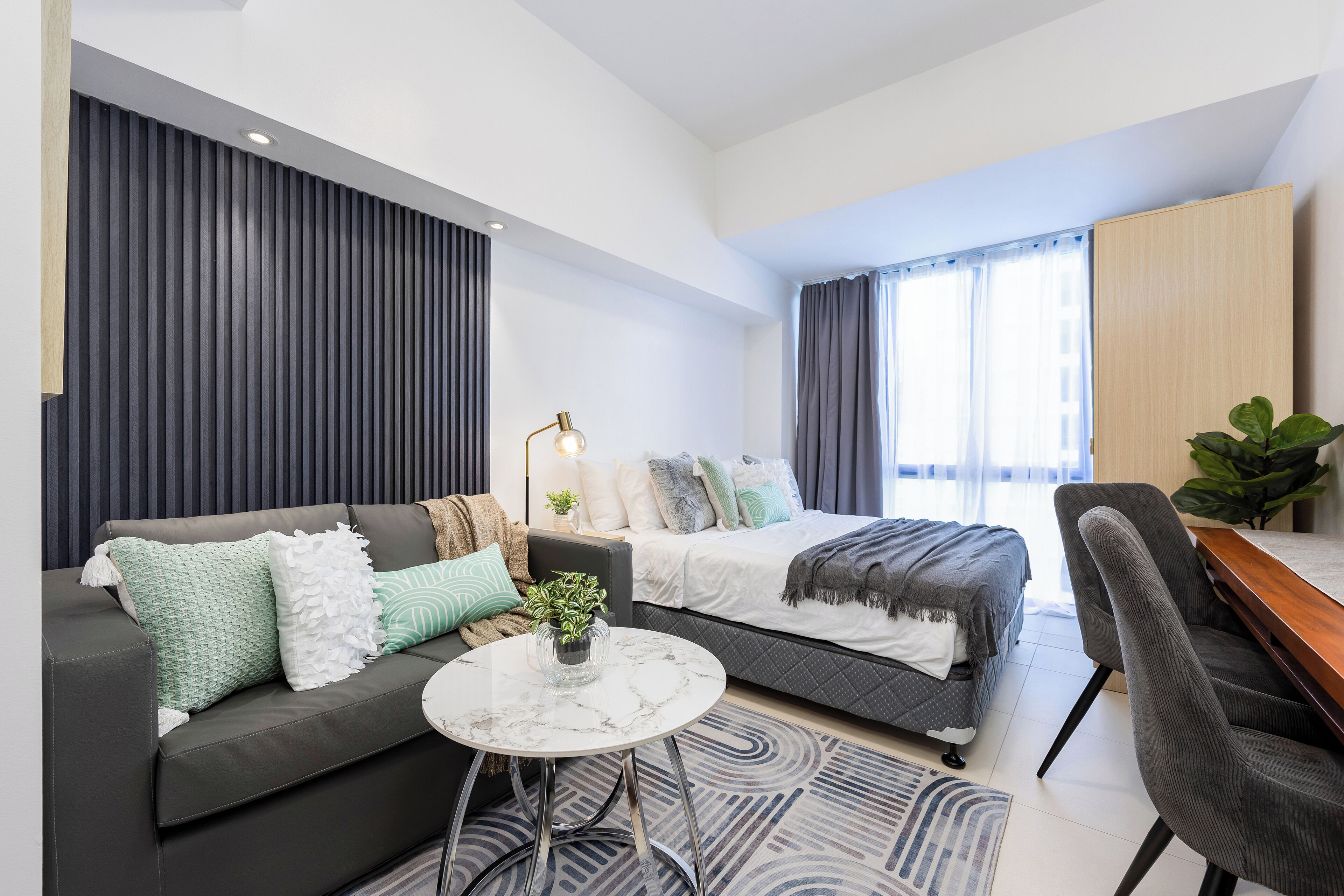 Un dormitorio moderno con cama, sofá, escritorio y una mesita de centro.