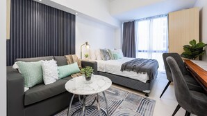 Een moderne slaapkamer met een bed, een bank, een bureau en een salontafel.