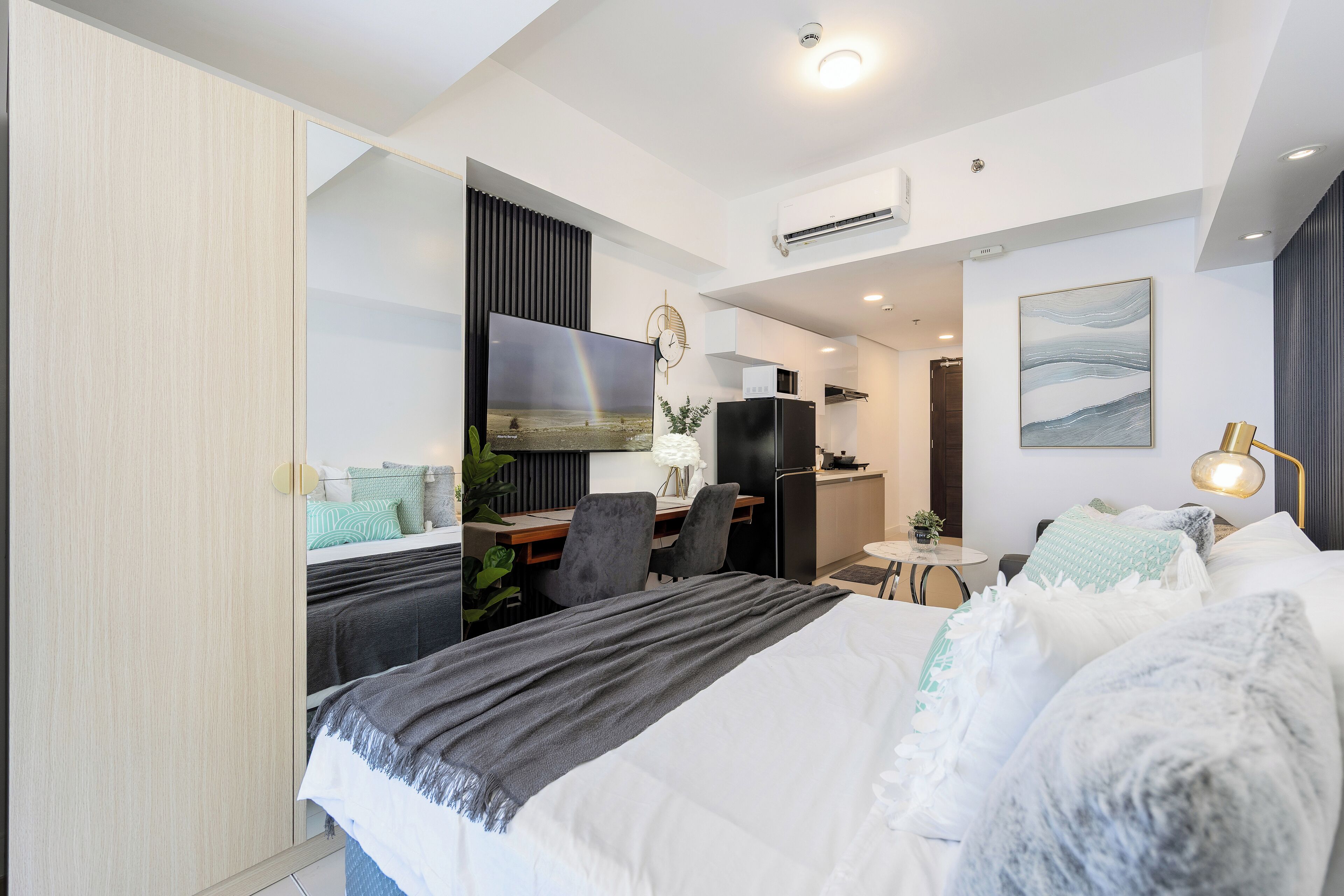 Una habitación de hotel moderna con cama, escritorio y kitchenette.