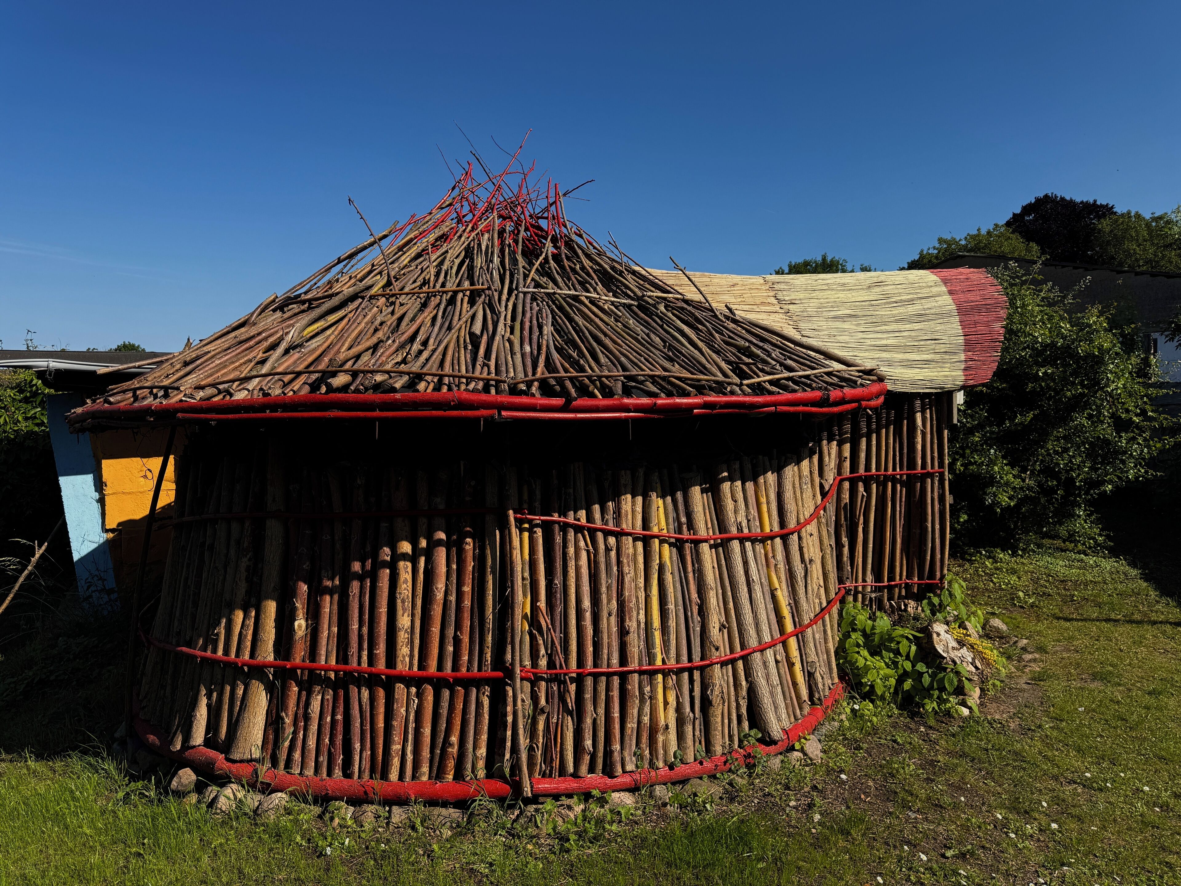 Eine traditionelle Hütte mit einem kegelförmigen Dach aus Ästen und einem flachen Dachbereich.