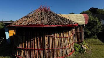 A traditional hut with a conical roof made of sticks and a flat roof section.