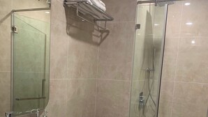 Un baño moderno con ducha de vidrio, lavamanos blanco y retrete.
