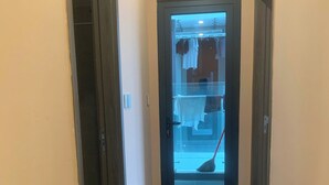 Un pasillo con piso de madera que conduce a una habitación con puerta de vidrio.
