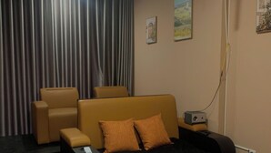 Un dormitorio con cama, sofá, sillón y mesita de noche con lámpara.
