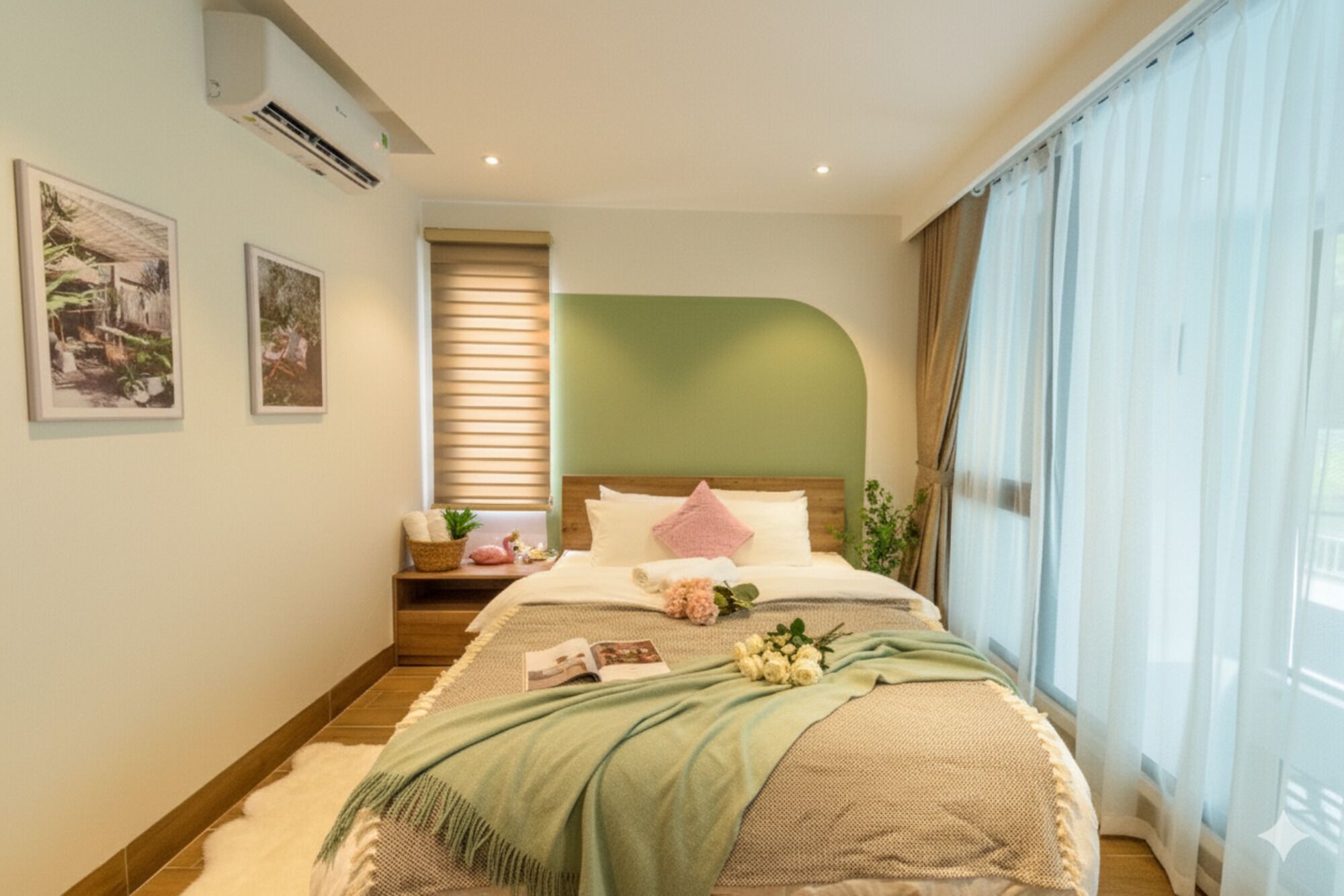 Un dormitorio con cama, una mesita de noche con lámpara, una ventana con cortinas y dos cuadros en la pared.