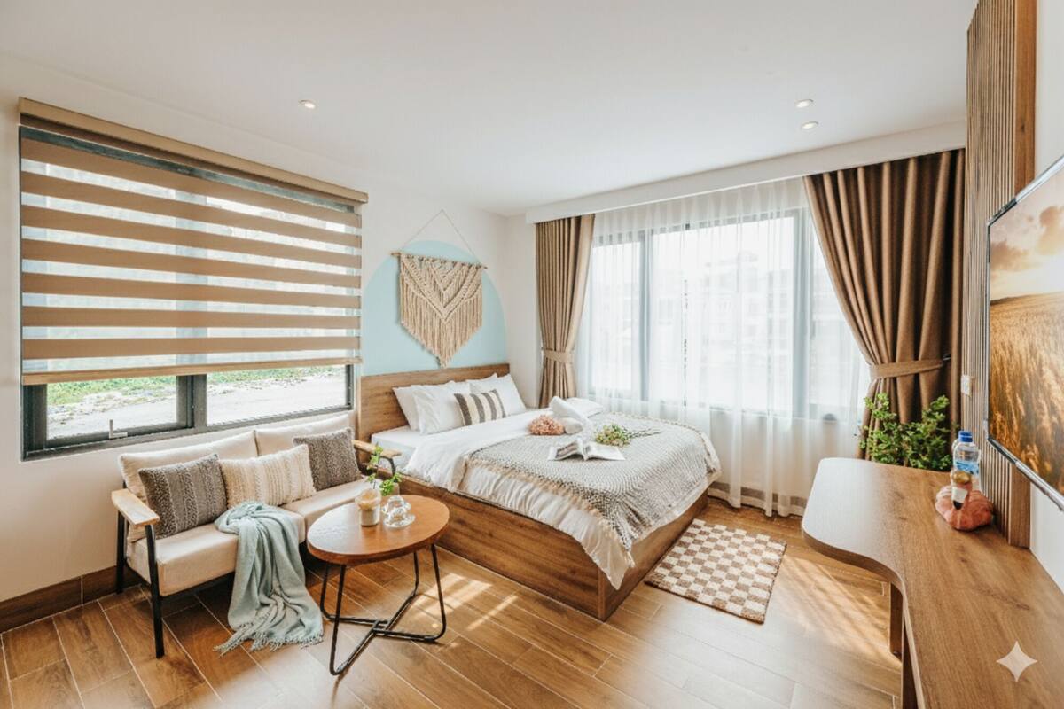 A modern bedroom with a bed, a sofa, a small table, and a chair.