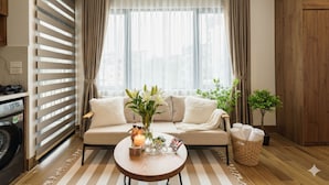 Sala de estar com sofá, mesa de centro com uma vela e uma pequena planta.