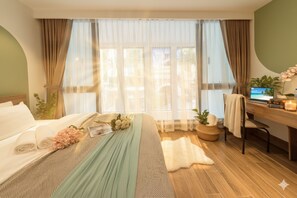 Habitación de hotel con cama, escritorio y ventana grande con cortinas translúcidas.
