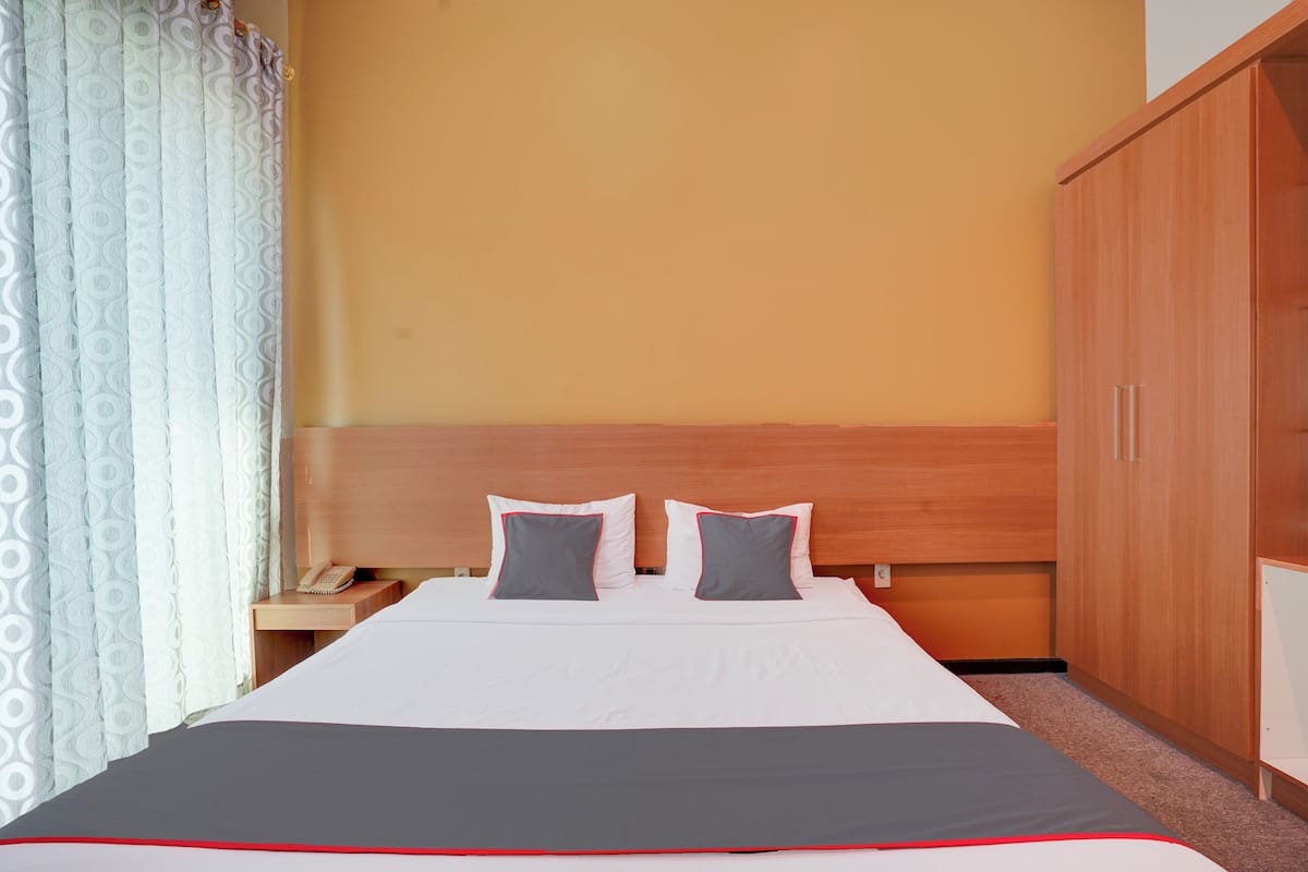 A neatly made bed with a white and gray bedspread, two pillows, and a wooden headboard.