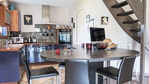 A modern kitchen with a central island, stainless steel appliances, and a staircase. - La Roche Blanche by Interhome (Hillion)