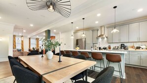 A modern kitchen with a central island, stainless steel appliances, and pendant lighting. - ★ HostWise Stays ★  Vibrant Getaway - Skyline Rooftop Deck & Garage (Pittsburgh)