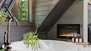 A modern outdoor hot tub with a wooden deck, a fireplace, and potted plants. - Custom Mountain Home · Hot Tub · Waterfall · 2.5 Acres · EV Charger (Placerville)