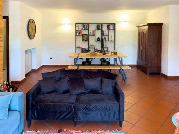 A living room with a black sofa, a wooden dining table, and a bookshelf.