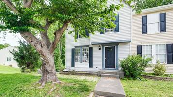 A two-story house with a front porch, a tree in the yard, and a well-maintained lawn.