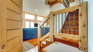 A wooden staircase with a view of a blue sofa and a patterned rug in the background. - Mtn-View Deck: Scenic Conway Log Cabin! (Conway)