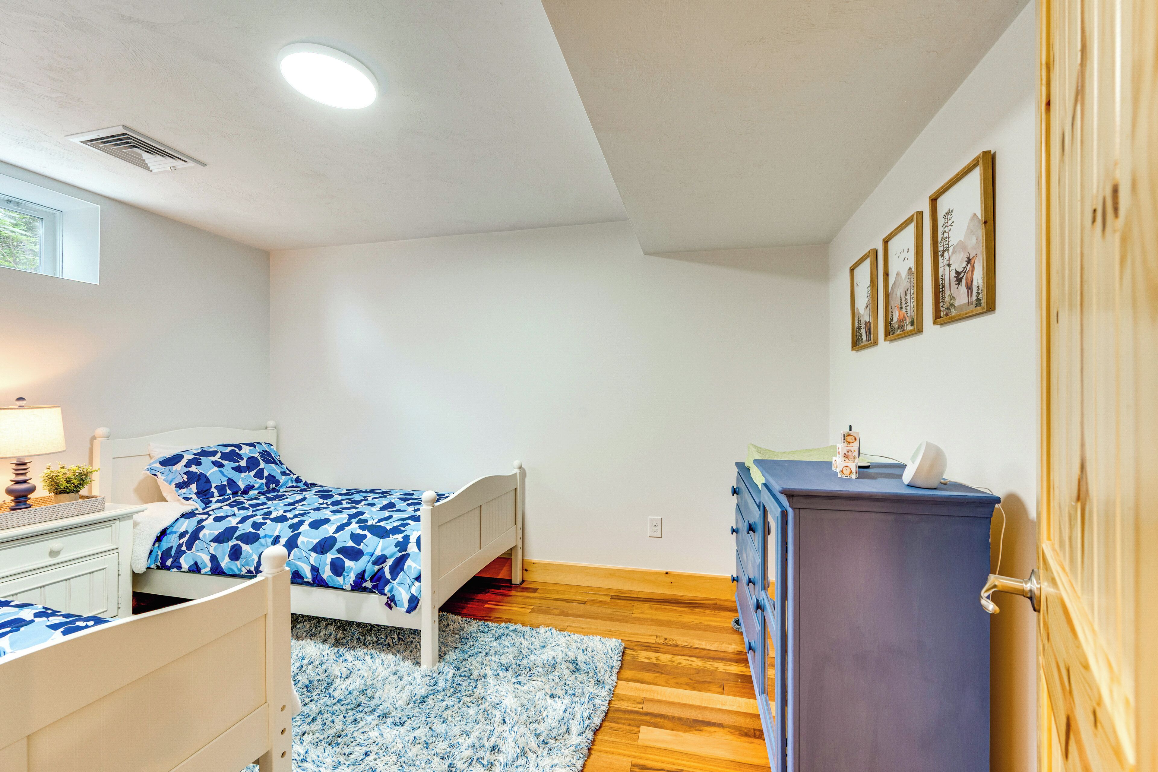 A bedroom with a bed, dresser, and a small desk with a lamp.