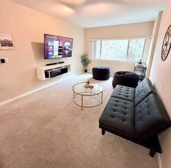A living room with a TV, sofa, coffee table, and a window.