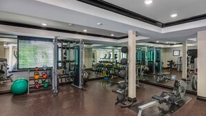 Une salle de sport équipée de divers appareils d’exercice, de miroirs et d’un ballon d’exercice vert.