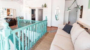 A spacious living area with a staircase, a sofa, and a dining area.