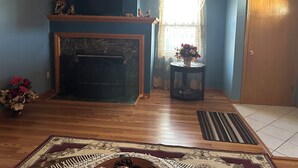 Una sala de estar con chimenea, una puerta de madera y una ventana con cortinas.