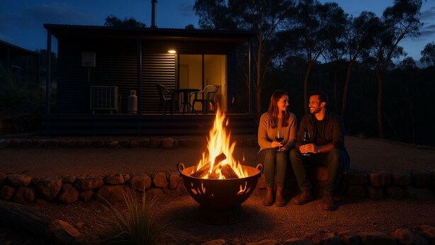 A cozy outdoor seating area with a fire pit, a small building with a porch, and a stone wall.