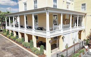 A two-story building with a covered porch and a small garden area.
