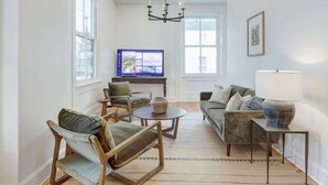 Ein Wohnzimmer mit Fernseher, zwei Sofas, einem Couchtisch und einer Deckenleuchte.