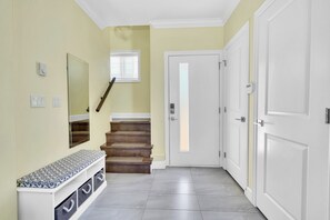 A hallway with a bench, a staircase, and a door.