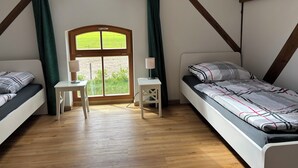 A room with two beds, a small table, and a window with a view of greenery. - Cozy vacation apartment / fitter's room for 1-6 persons near Berlin FeWo 8. (Liebenwalde)