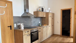 A compact kitchen with wooden cabinets, a built-in oven, and a microwave. - Cozy vacation apartment / fitter's room for 1-6 persons near Berlin FeWo 8. (Liebenwalde)