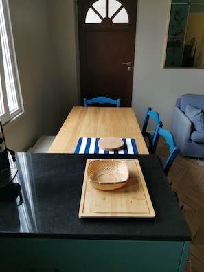A dining area with a wooden table, blue chairs, and a black countertop.