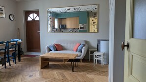 A living room with a sofa, coffee table, and a dining area with chairs and a table.