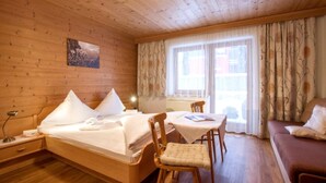 A wooden cabin room with a bed, a table with chairs, and a sofa. - Apartment in Fugen Near Spieljochbahn (Fuegen)