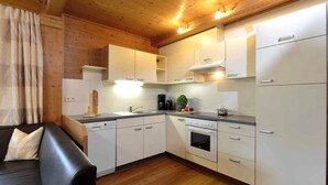 A modern kitchen with white cabinets, a black countertop, and wooden flooring. - Apartment in Fugen Near Spieljochbahn (Fuegen)