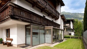 A modern building with a wooden balcony, a glass door entrance, and a small garden area. - Apartment in Fugen Near Spieljochbahn (Fuegen)