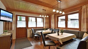 A cozy dining area with wooden walls, a TV mounted on the wall, and a table with chairs and a bench. - Apartment in Fugen Near Spieljochbahn (Fuegen)