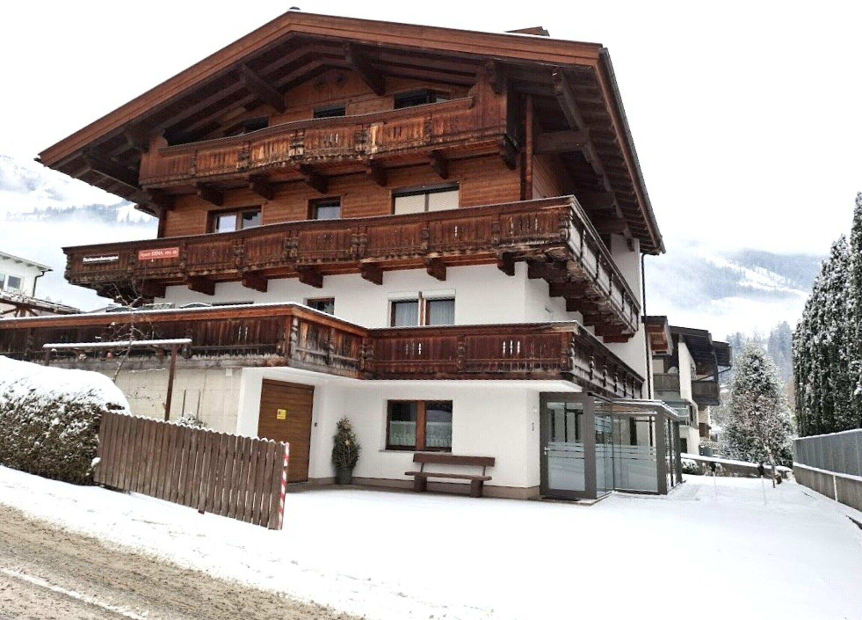 A multi-story wooden building with balconies, a bench, and a door.