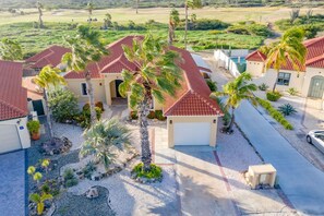 Un quartier résidentiel où les maisons se distinguent par leurs toits recouverts de tuiles rouges, et qui est entouré de palmiers et de cactus.